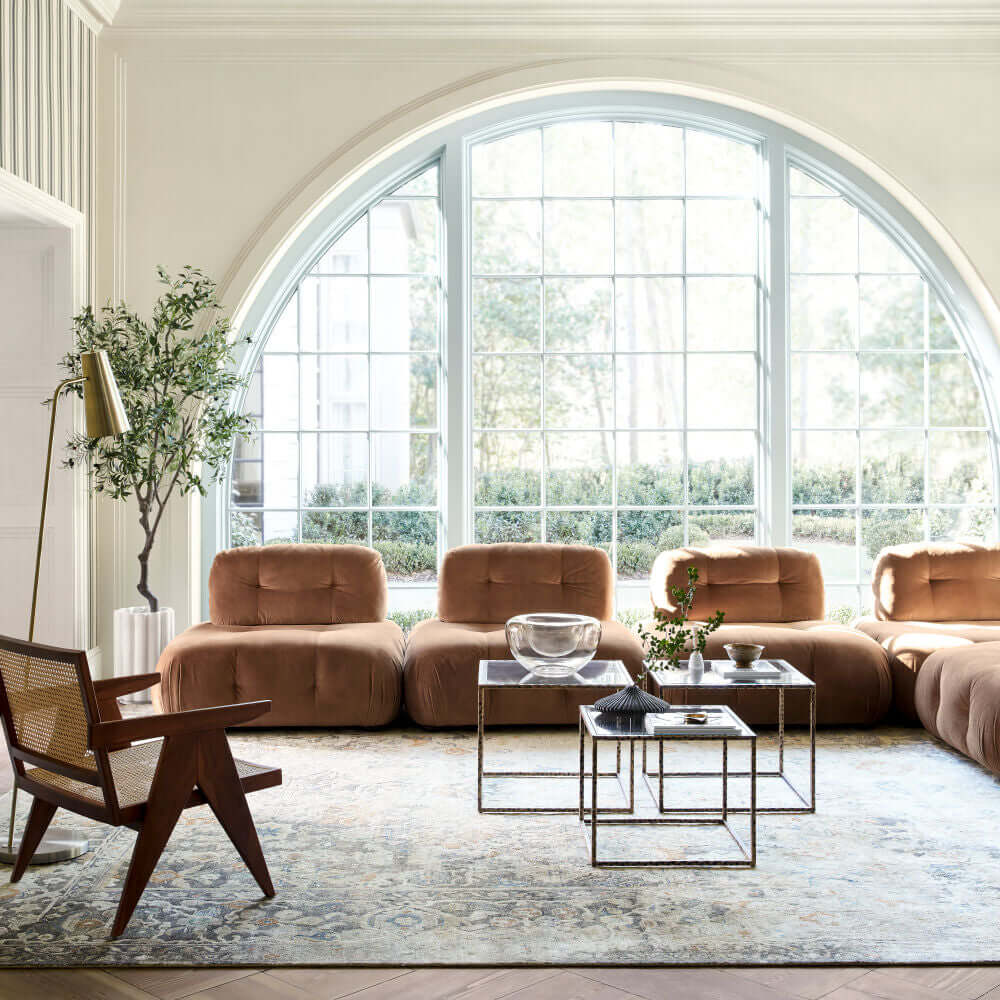 Bright living room with large windows and rattan dining arm chairs.