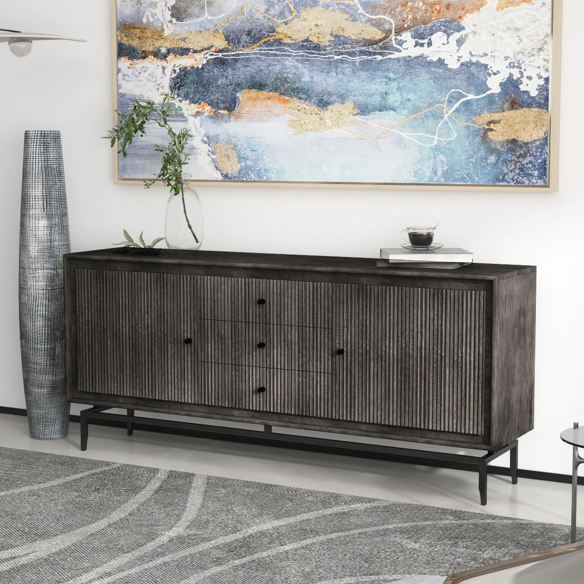 Black sideboard with fluted panels and minimalist décor, styled with greenery and artistic wall accents.