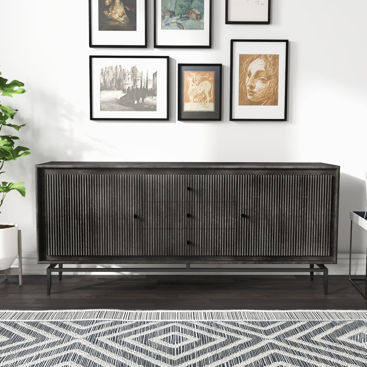 Black contemporary sideboard with fluted doors under gallery wall in a modern living room.