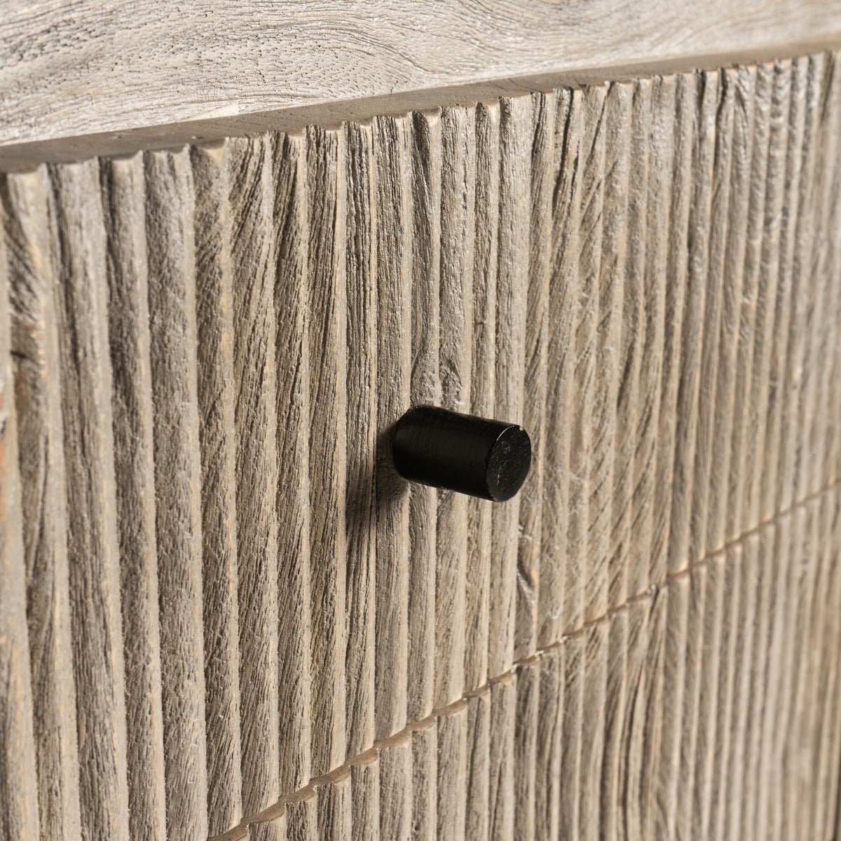 Detailed close-up of the black metal handles on fluted wood cabinet doors.