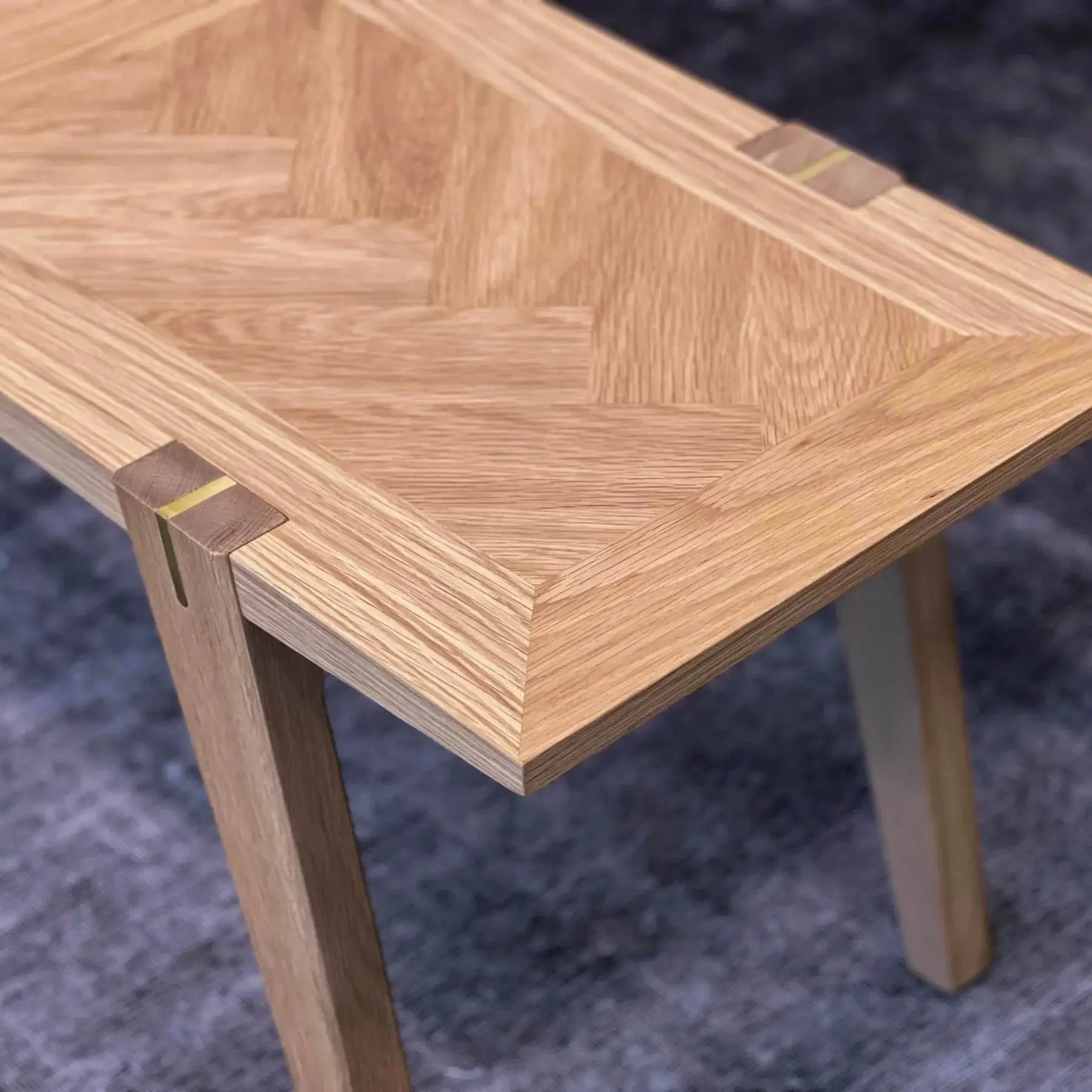  Close-up of Colton large dining bench detailing the brass inlay accents on natural oak wood.