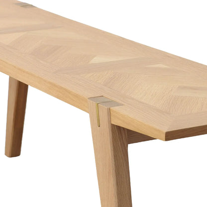 Side angle of the Colton oak wood dining bench, showing its sleek design with brass inlay and angled wooden legs.