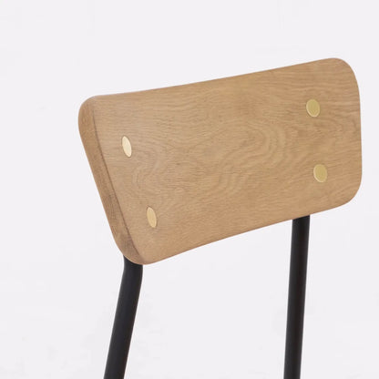 Close-up of the Colton solid oak dining chair's natural oak backrest with brass accent details.