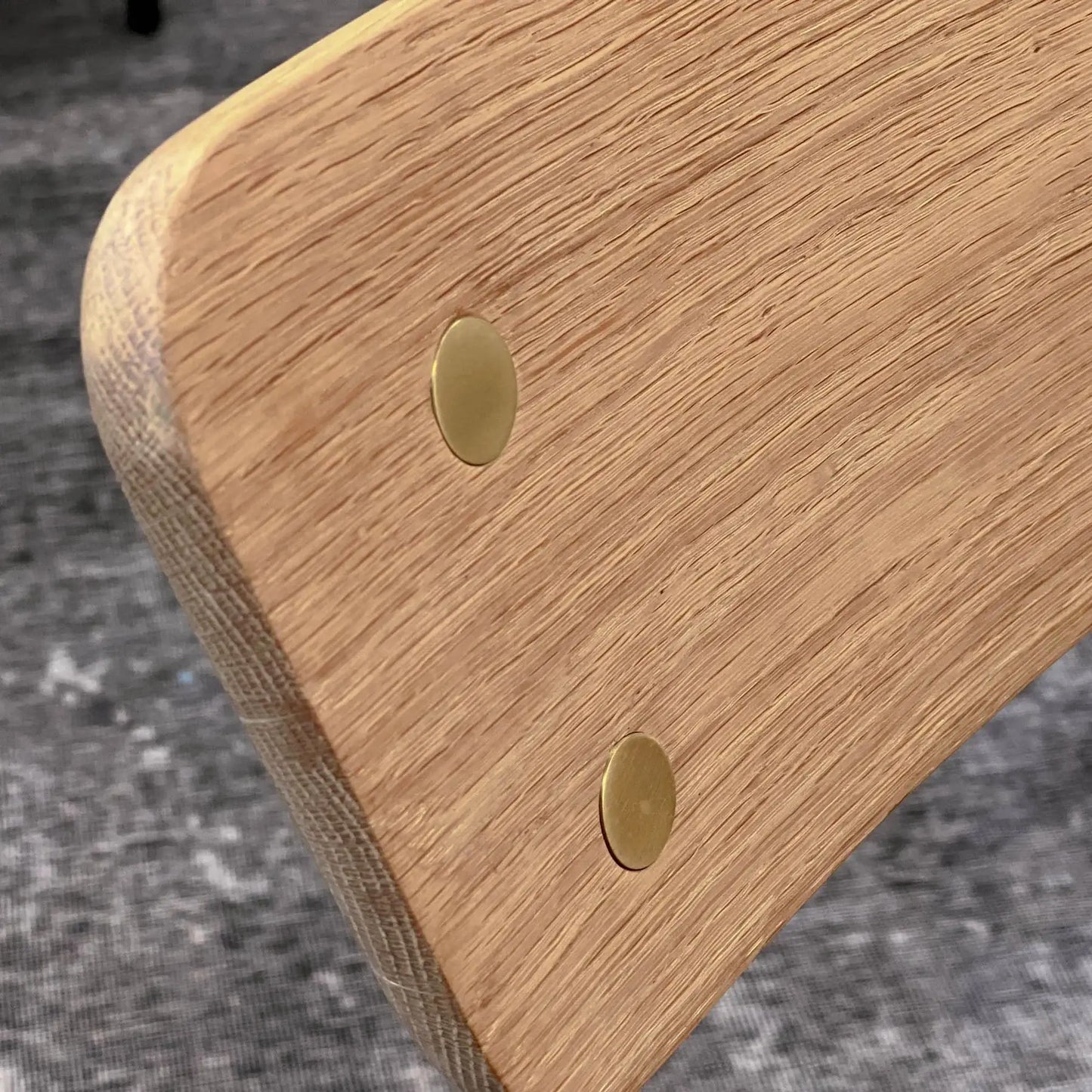 Close-up of brass accent on the oak wood backrest of the Colton solid oak dining chair.