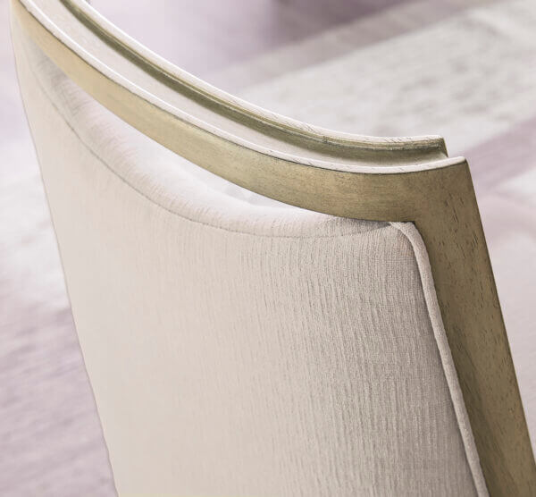 Close-up detail of Cove Dining Arm Chair's upholstery and curved back design in mushroom fabric.