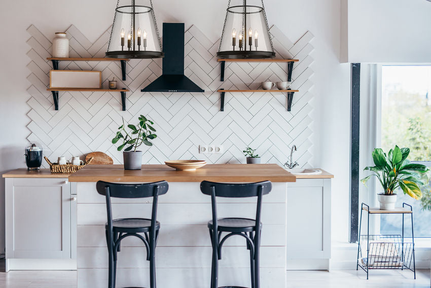 Matte black four-light pendants illuminating modern kitchen interior.