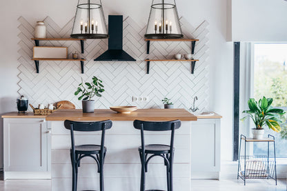 Matte black four-light pendants illuminating modern kitchen interior.