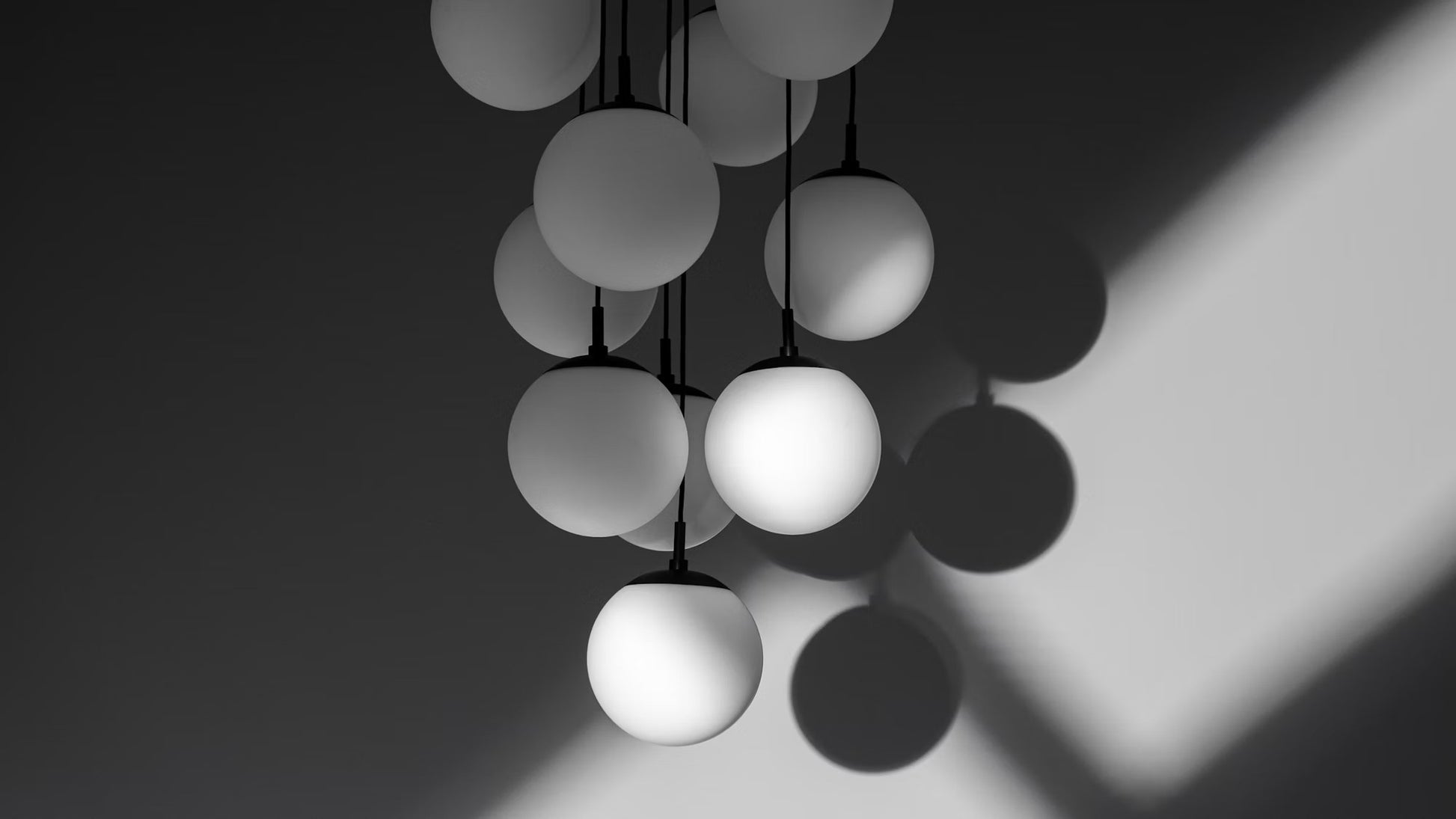 Stunning chandelier with frosted glass globes casting dramatic shadows against a dark background.