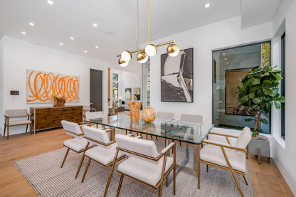modern gold chandelier above glass dining table.