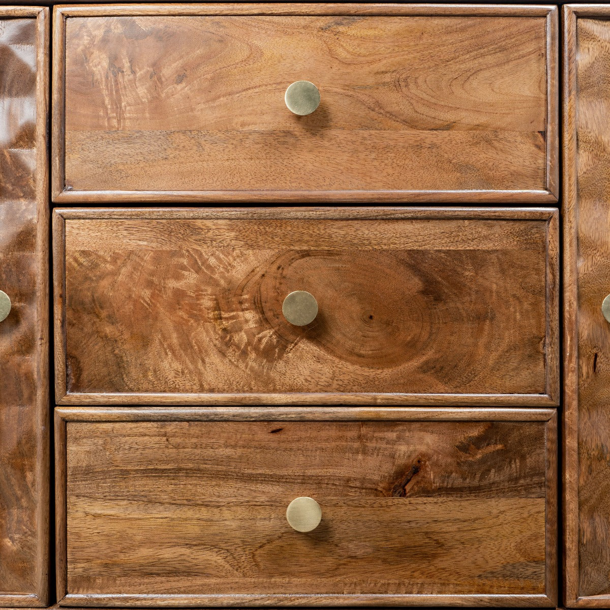 Front-facing close-up of drawers with gold handles and natural wood texture.