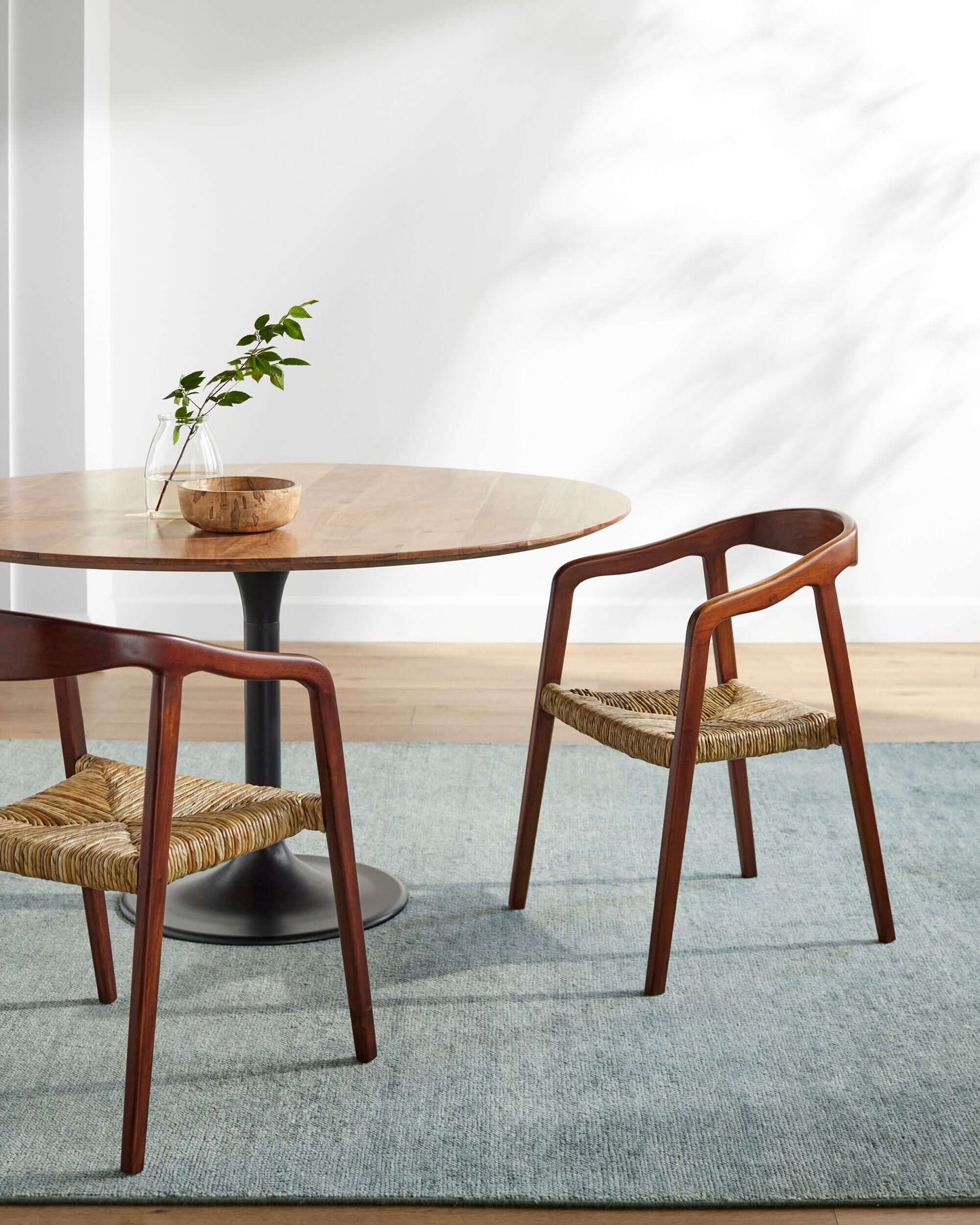 Side view of the Hefei Dining Arm Chair showing teak wood frame and seagrass seat in modern dining room.