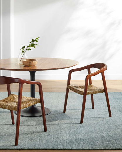 Side view of the Hefei Dining Arm Chair showing teak wood frame and seagrass seat in modern dining room.