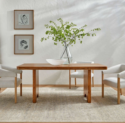 The Joiner Dining Table styled in a modern dining room with white chairs and minimalist decor.