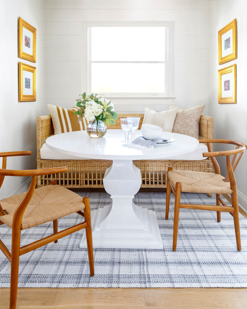  A cozy dining nook featuring brown modern teak wood dining chairs with seagrass seats.