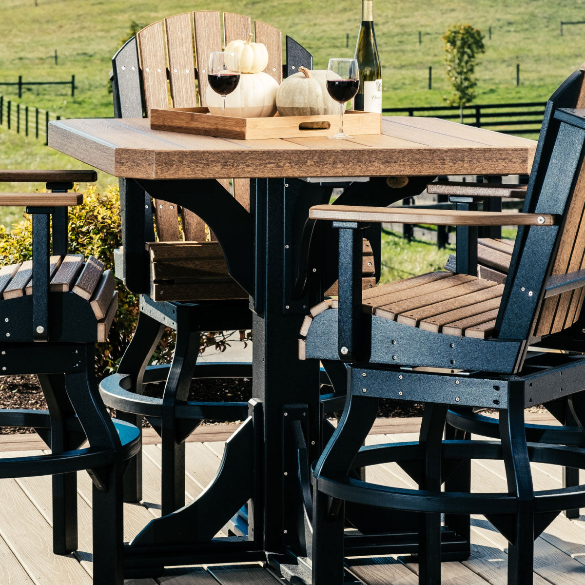 Outdoor setting with an Antique Mahogany and Black counter height table, paired with matching chairs and adorned with wine glasses and pumpkins, set against a picturesque countryside backdrop