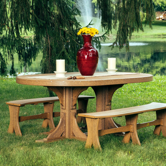 Idyllic outdoor dining setup featuring a Poly Wood 4'x6' Oval Dining Table with matching benches in a lush green park by a serene lake, adorned with a red vase and candles.