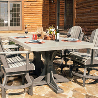 A Dove Gray and Slate outdoor dining set with a rectangular table and four Adirondack-style chairs, set with dinnerware and wine glasses, on a stone patio in front of a wooden cabin.