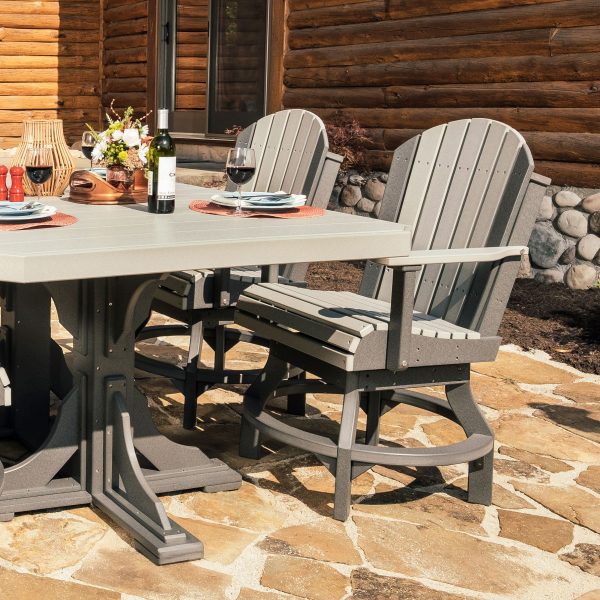 LuxCraft Adirondack Dining Swivel Chair set on a stone patio, accessorized with a dining table setup featuring wine and plates, against a log cabin background.