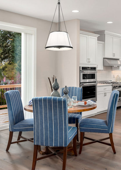 matte black pendant light illuminating breakfast nook with blue chairs