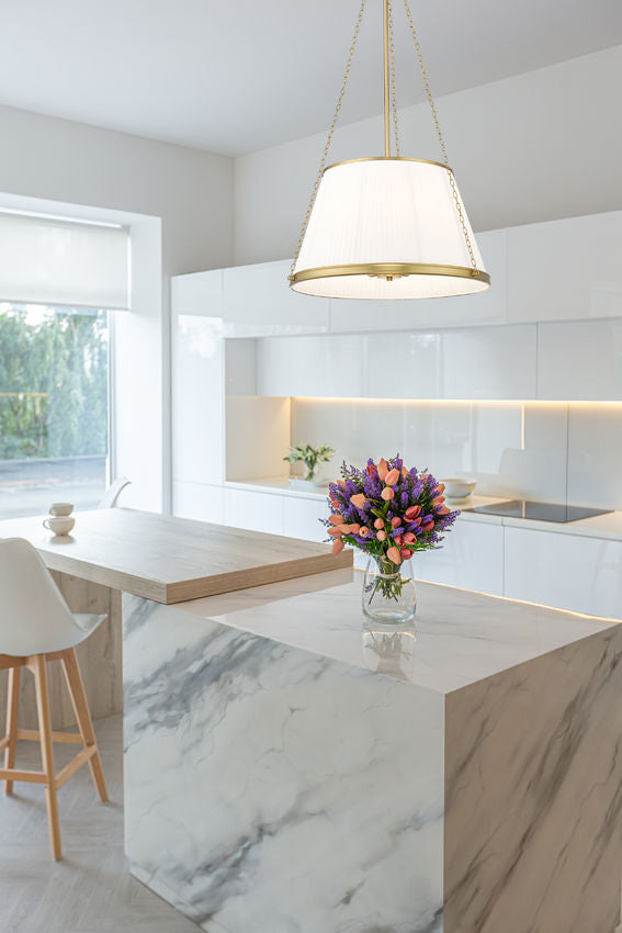 modern gold six-light pendant illuminating white marble kitchen island.