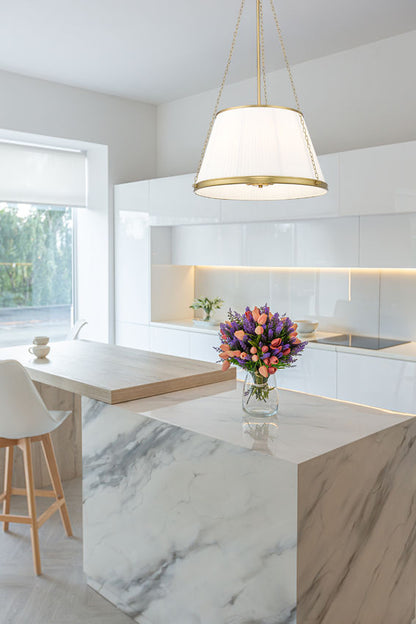 modern gold six-light pendant illuminating white marble kitchen island.