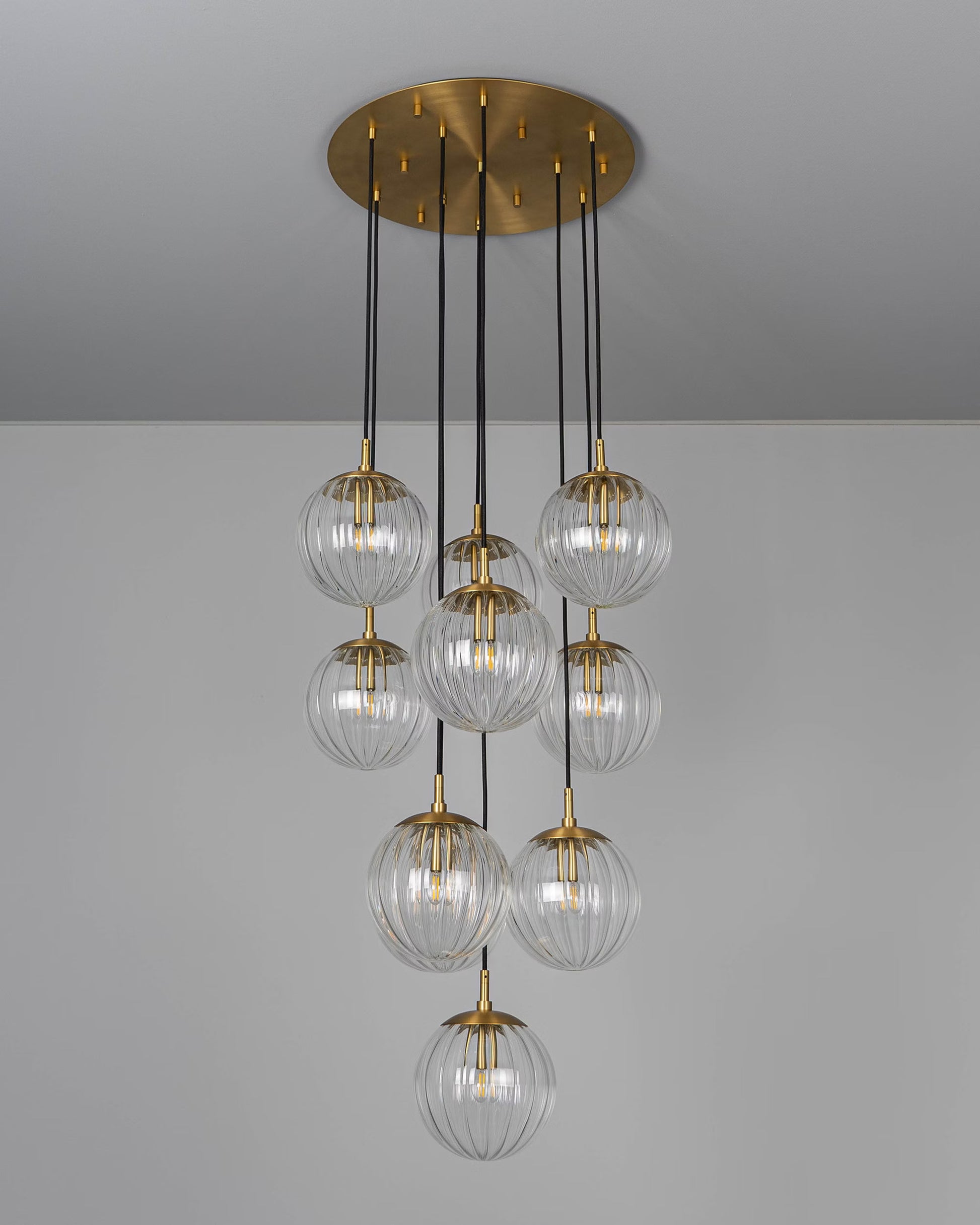 Sleek modern chandelier with clear glass globes and brass fittings, unlit for a minimalist aesthetic.