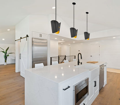 Trio of modern one-light pendants matte black over white island.