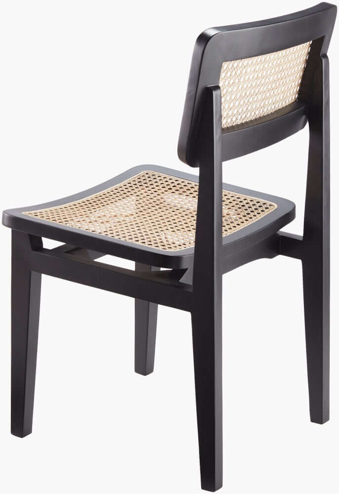 Angled view of the black finish Surya Arxan dining chair, showcasing the sleek frame and natural rattan details.