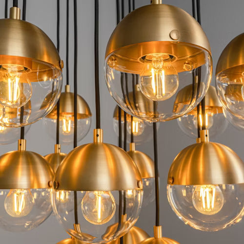 Close-up of handblown lit glass globes and burnished brass finish.