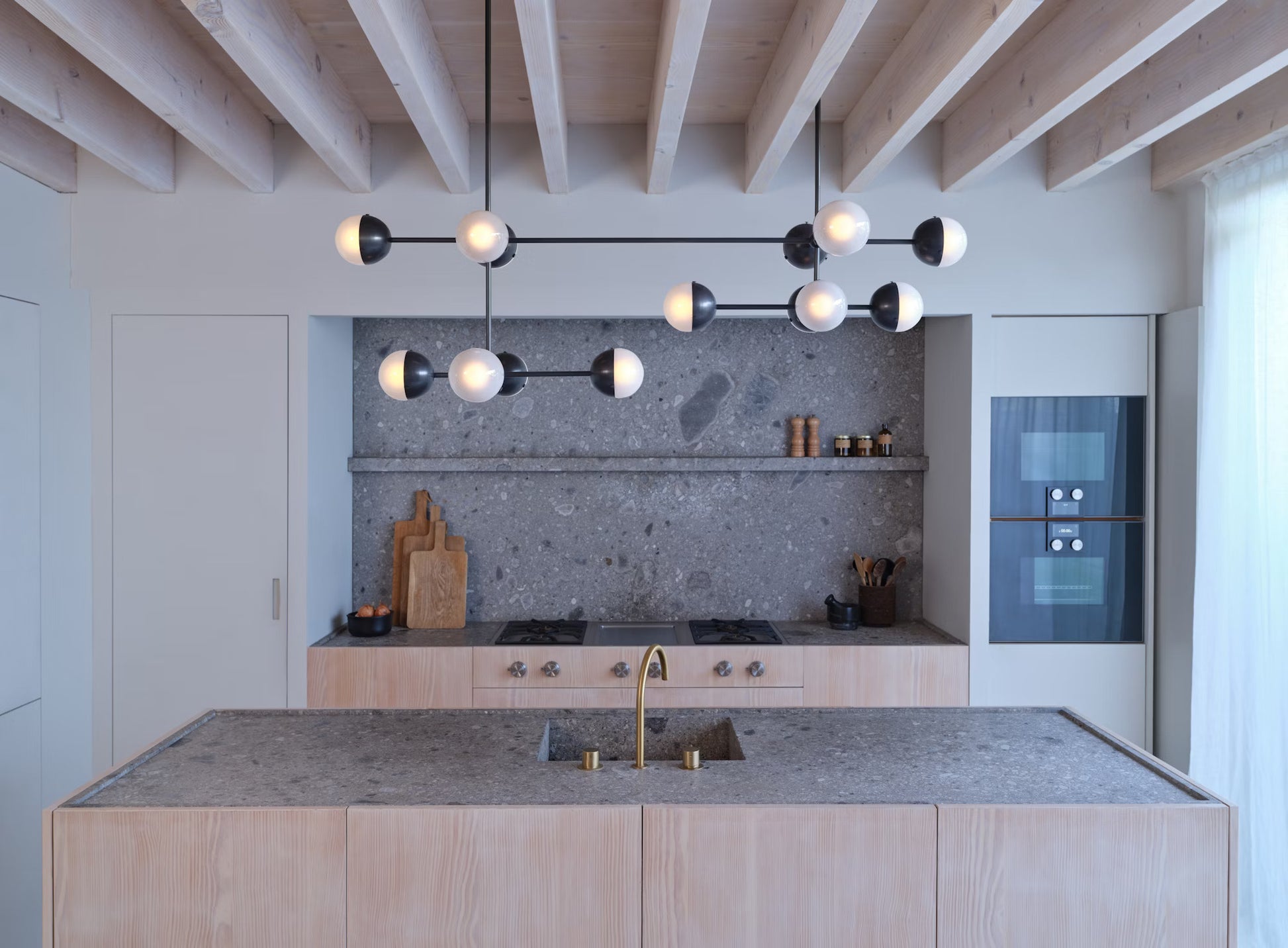 Molecule Linear Chandelier hanging above a modern kitchen island with warm, inviting light.