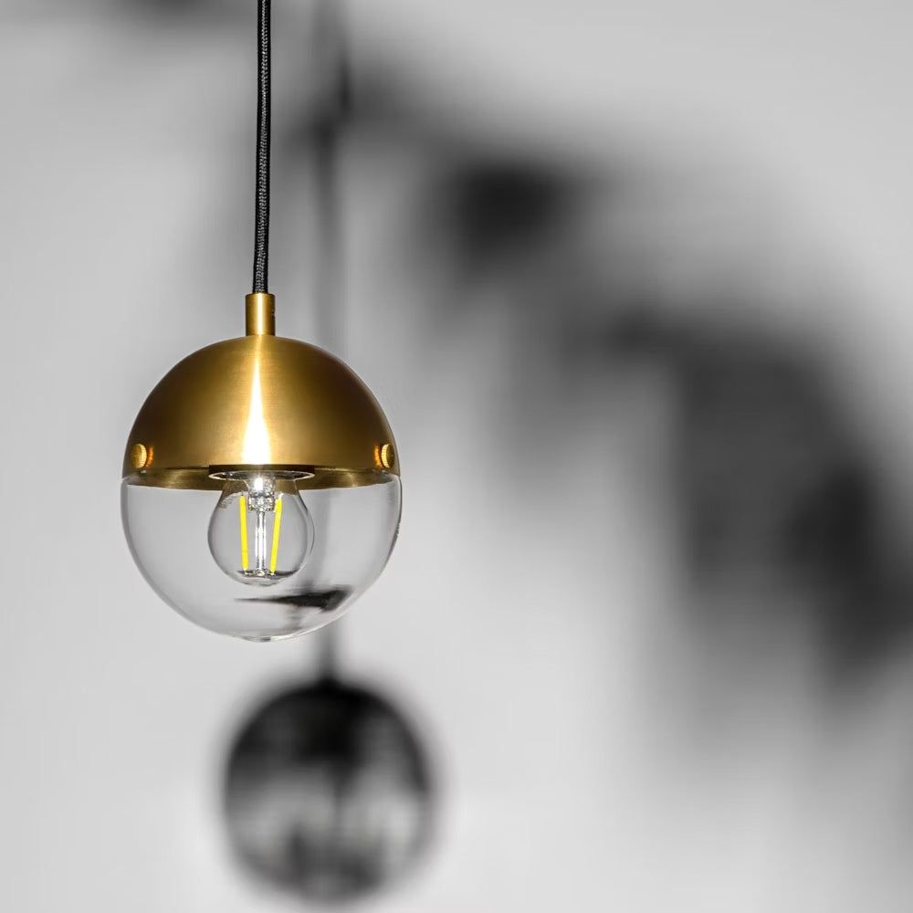 Close-up of Molecule Pendant Light with transparent glass and brass finish.