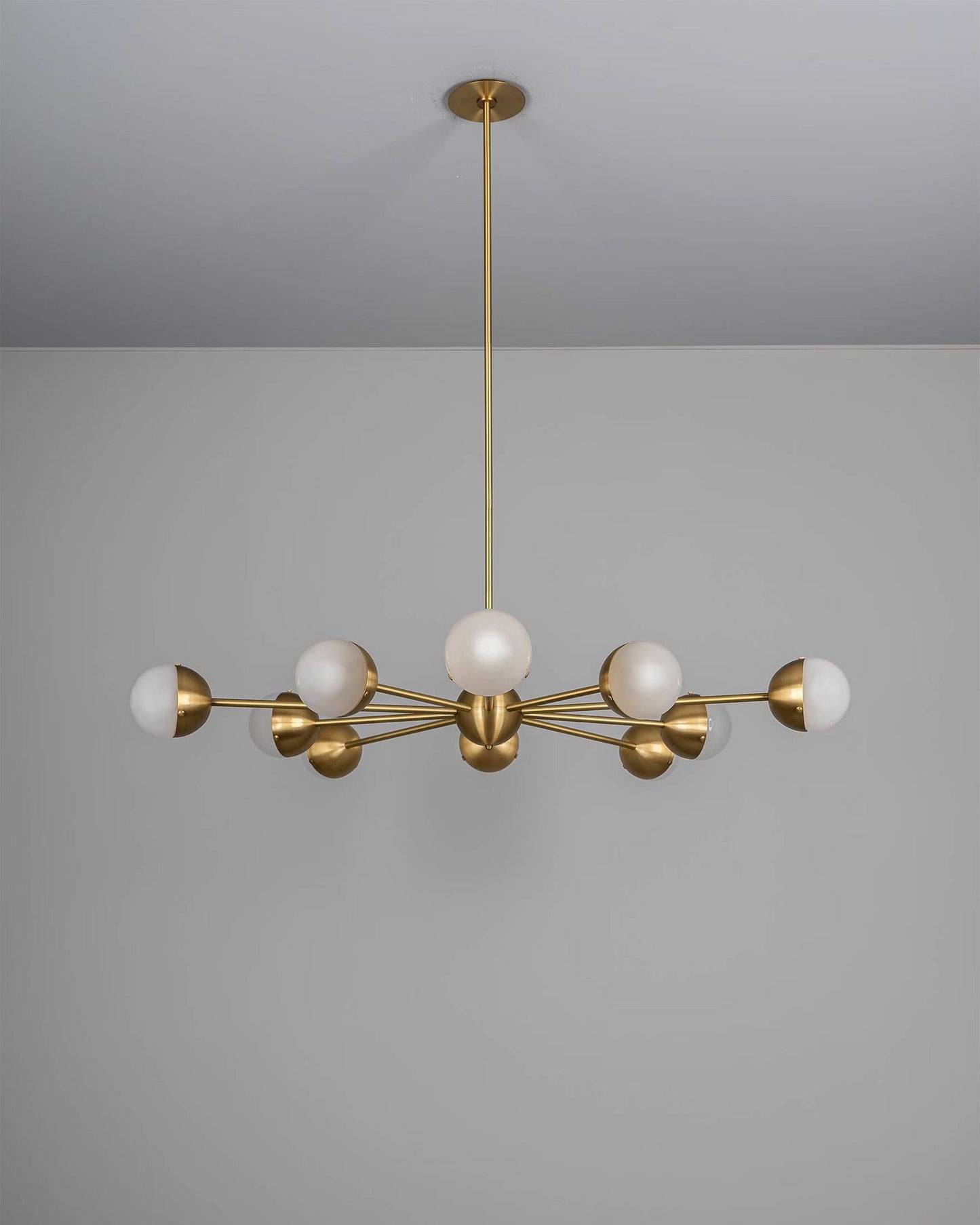 Molecule Spark Round 10 Chandelier with frosted glass globes and brass arms, turned off.