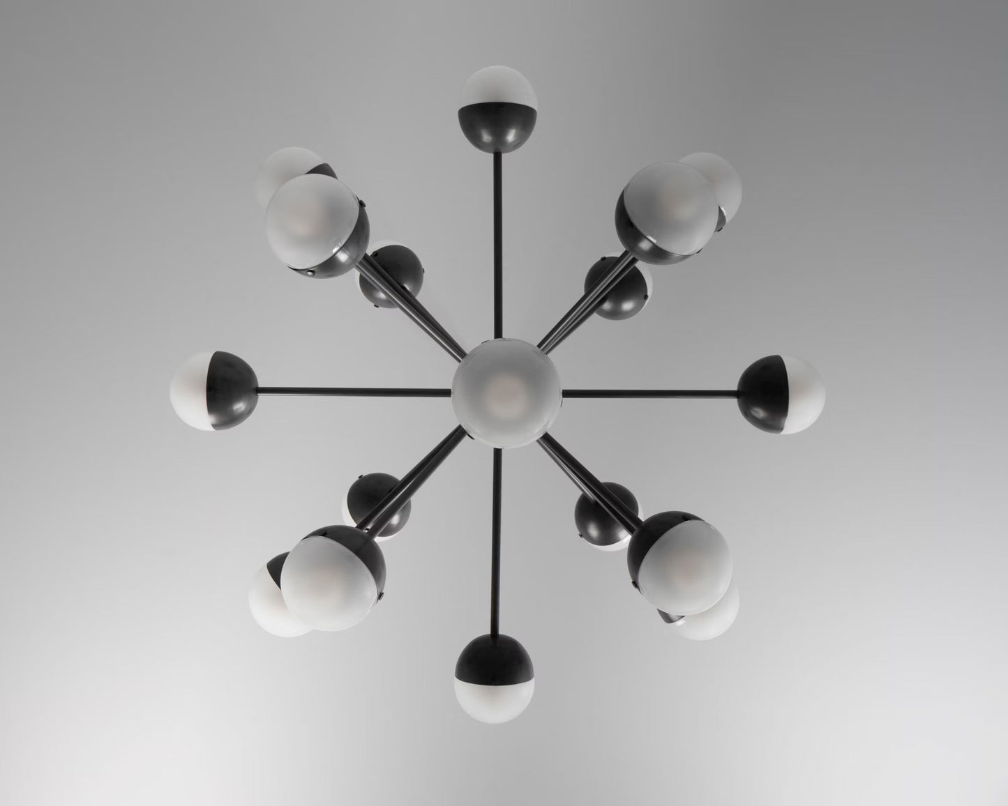 Overhead view of a black chandelier with frosted glass globes.