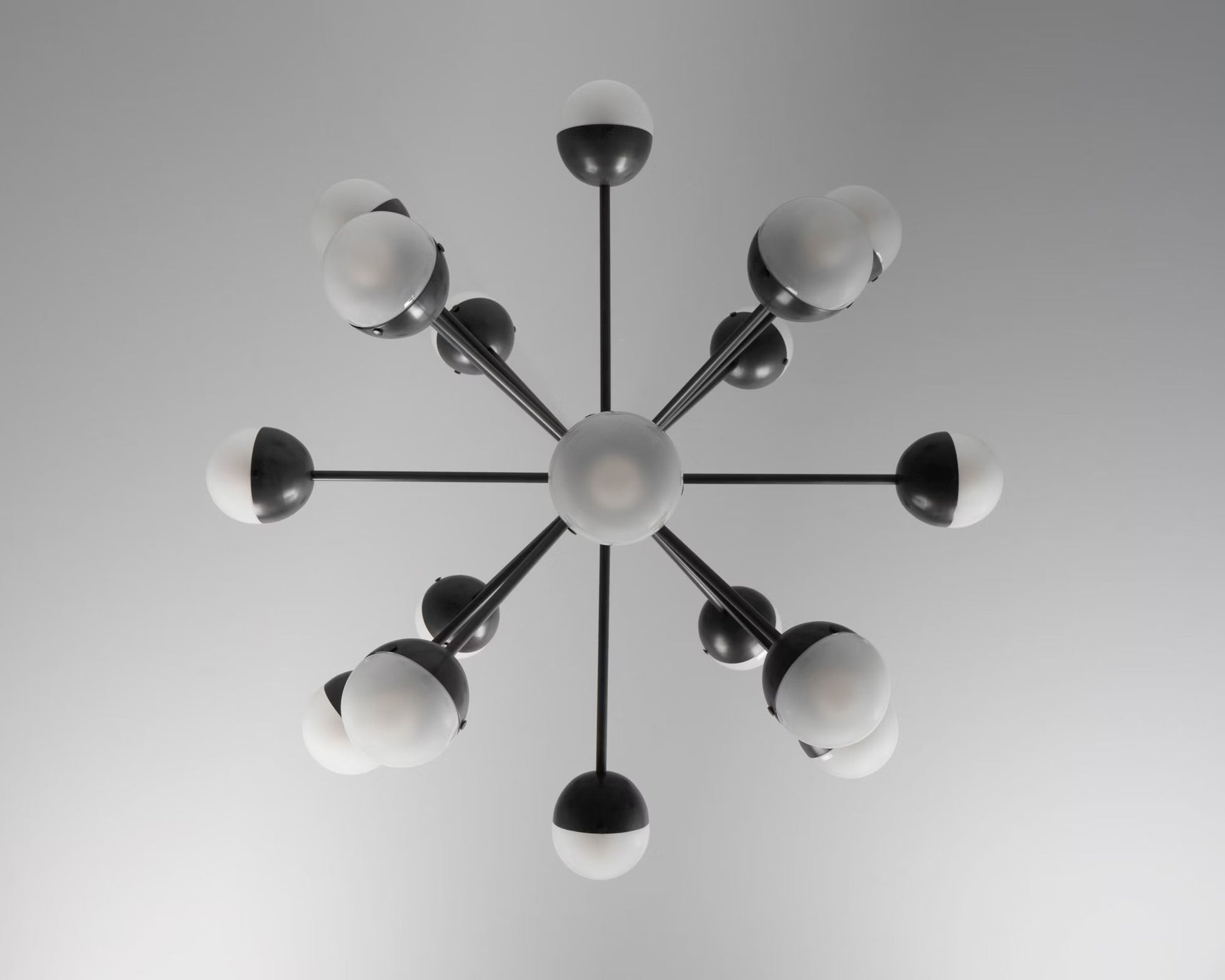 Overhead view of a black chandelier with frosted glass globes.