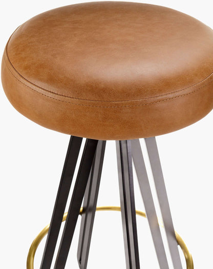 Close-up of the Oberon Bar Stool by Surya, showing the sleek brown leather seat and durable steel base with brass accents.