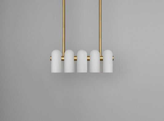 Brass linear chandelier with frosted glass cylinders and sleek design, suspended against a gray backdrop.