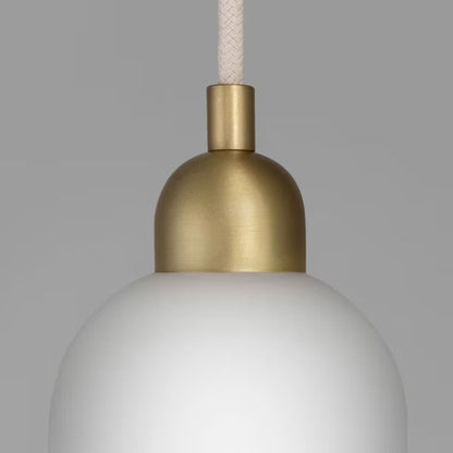 Close-up of Odyssey Pendant Light showing brass body and handblown opal glass shade.