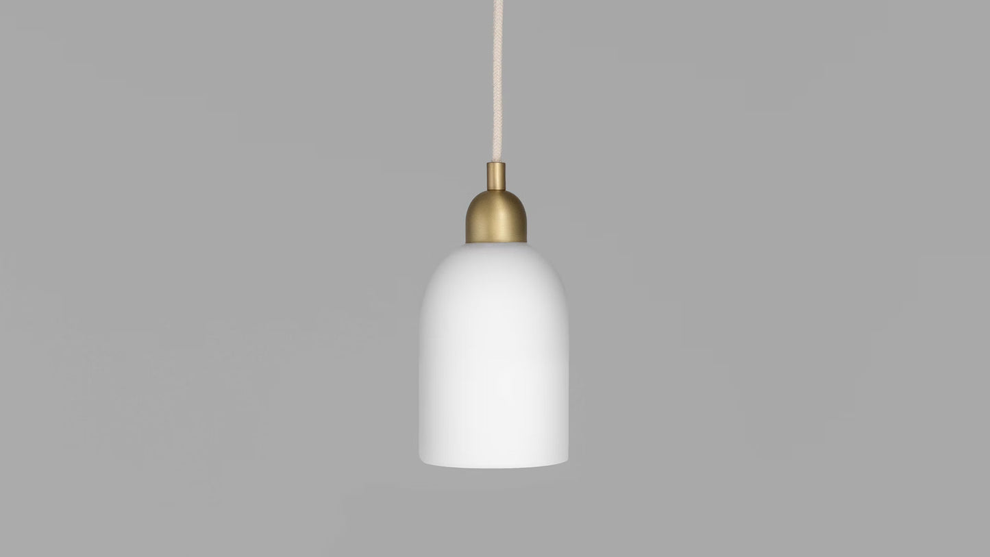 Odyssey Pendant Light turned off with brass finish and sleek white glass shade on a gray background.