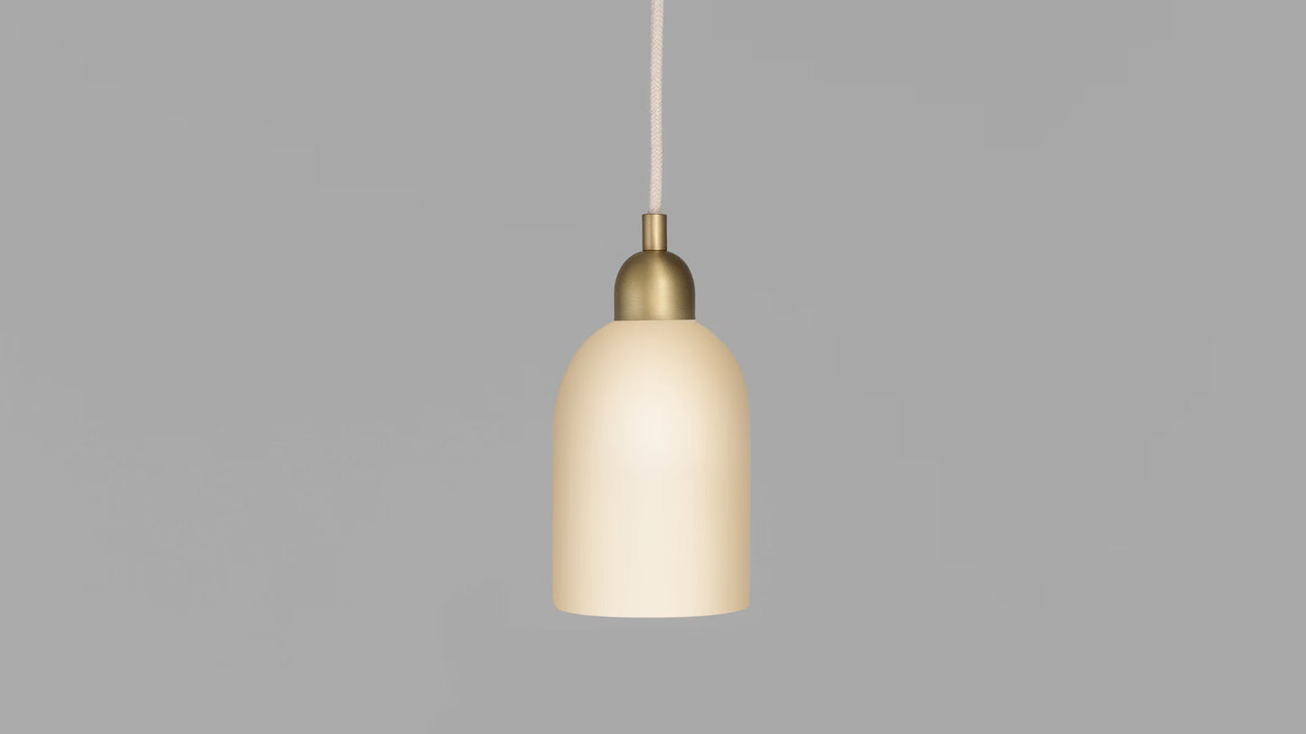 Odyssey Pendant Light on, glowing warmly with brass finish and white glass shade.