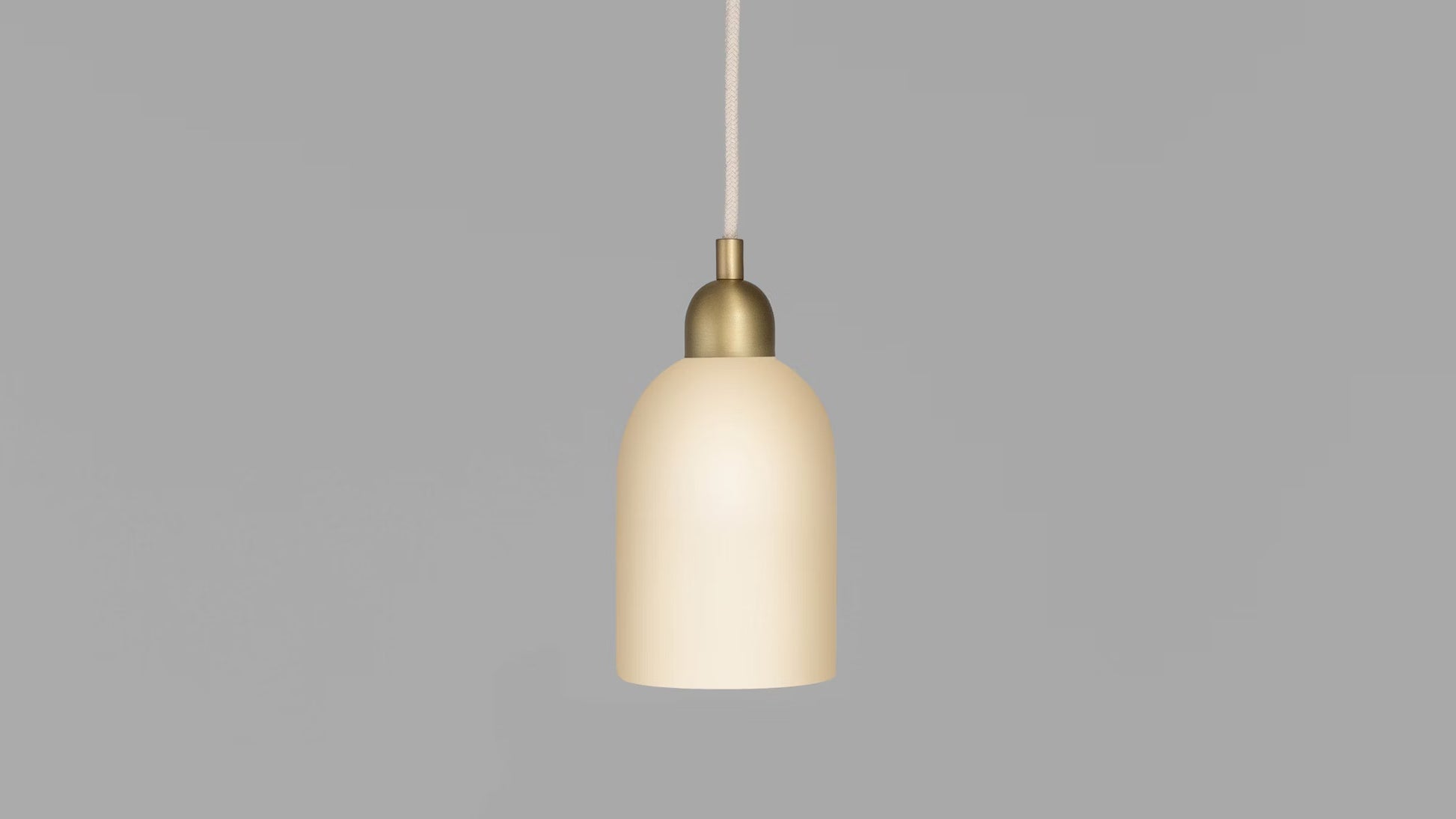 Odyssey Pendant Light on, glowing warmly with brass finish and white glass shade.