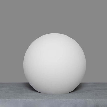 Single opal matte globe on a textured surface, minimalist elegance.