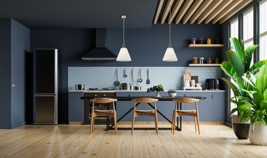 polished nickel pendants above navy modern kitchen.