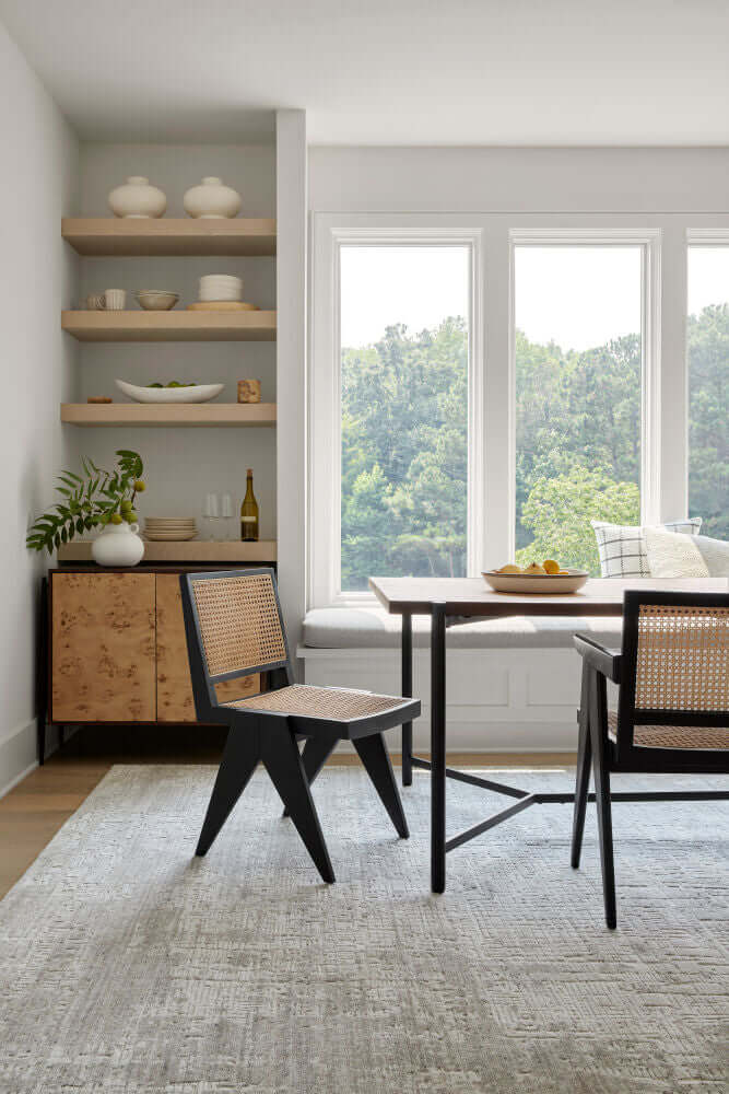 Hague RattN Dining Arm Chairs arranged around a dining table in a bright, modern dining room with large windows.