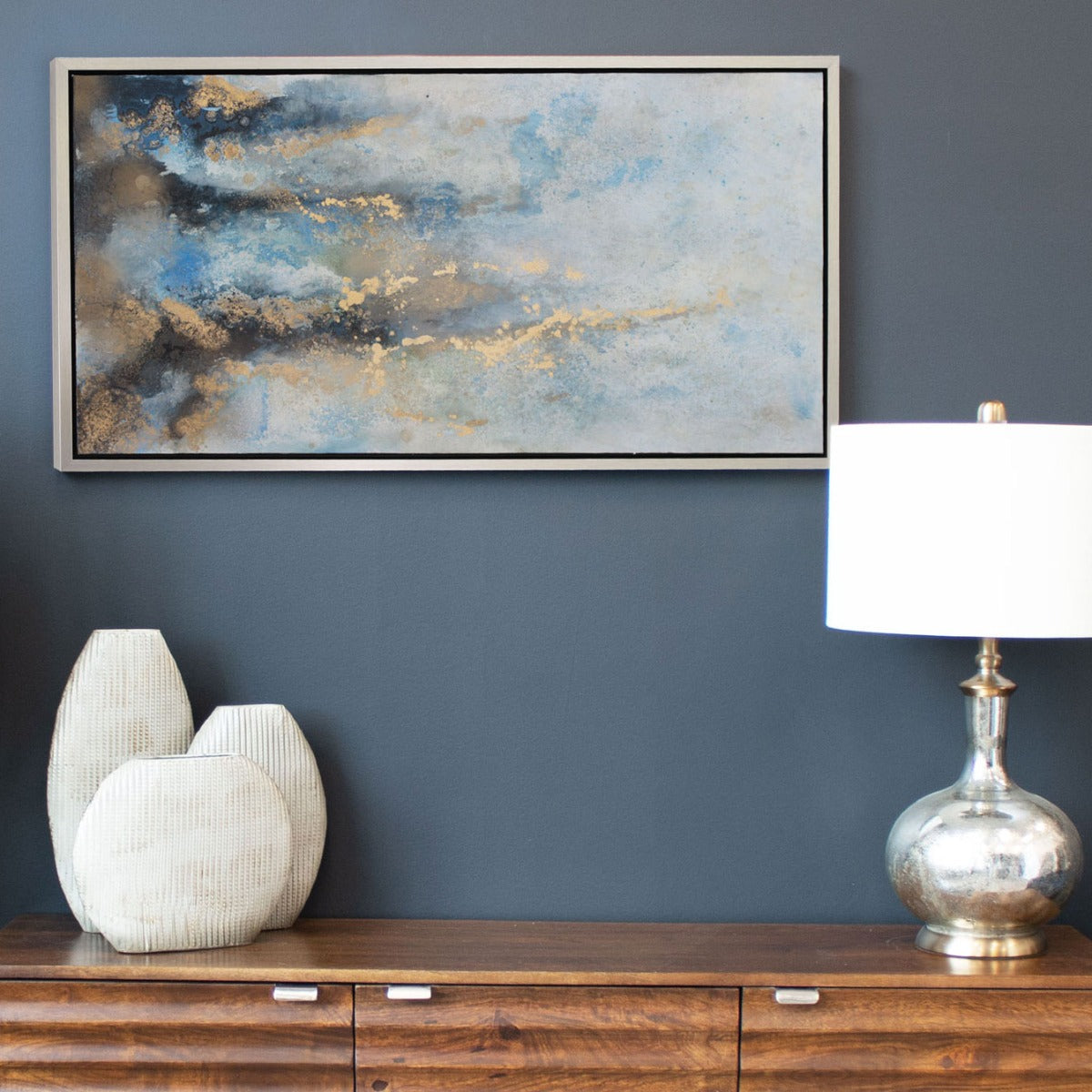 Abstract blue and gold canvas displayed above a dining room console with stylish decor elements.