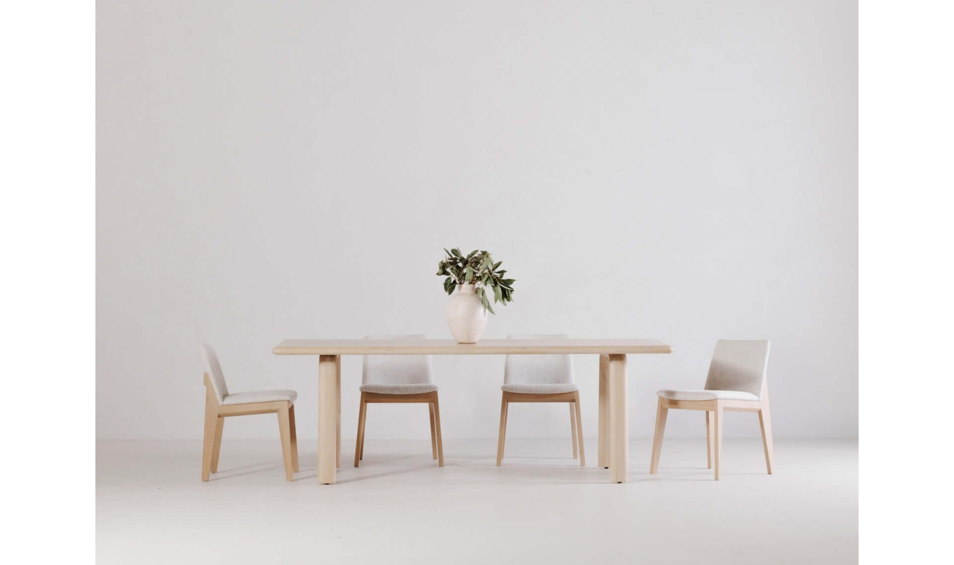 Malibu dining table with white chairs in a minimalist setting.