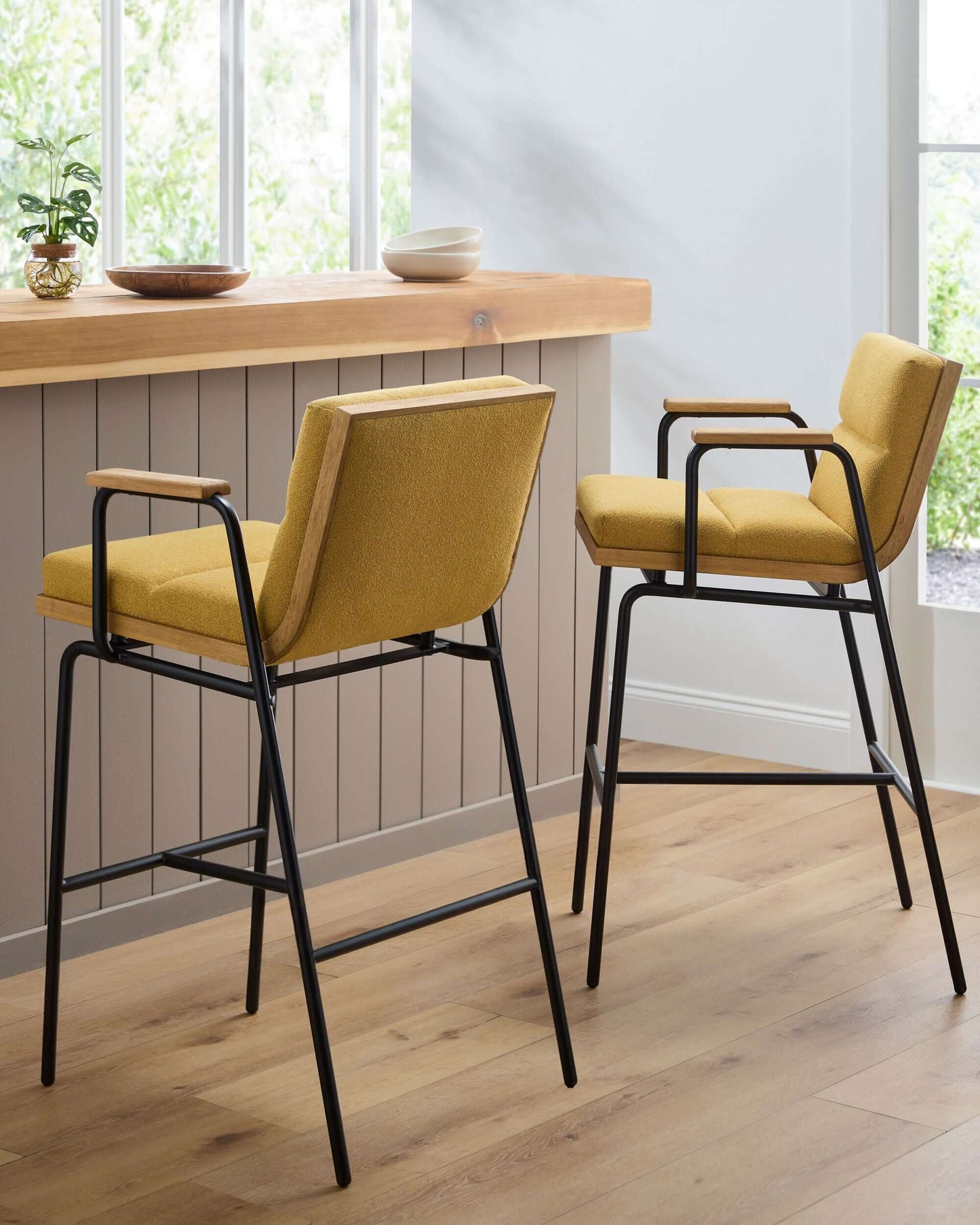  Stylish setting featuring two Thomas Bar Stools by Surya at a wooden counter, emphasizing the bold yellow seats and industrial design.