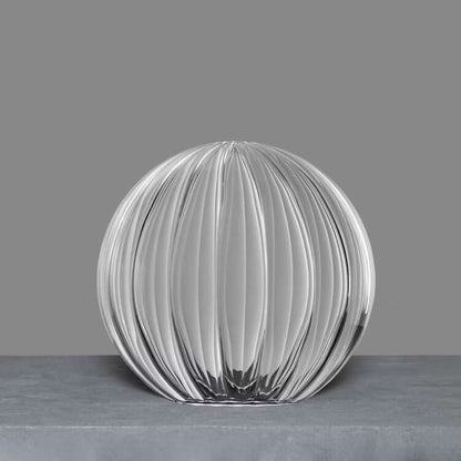 Single transparent ribbon glass globe with intricate detailing on a neutral background.