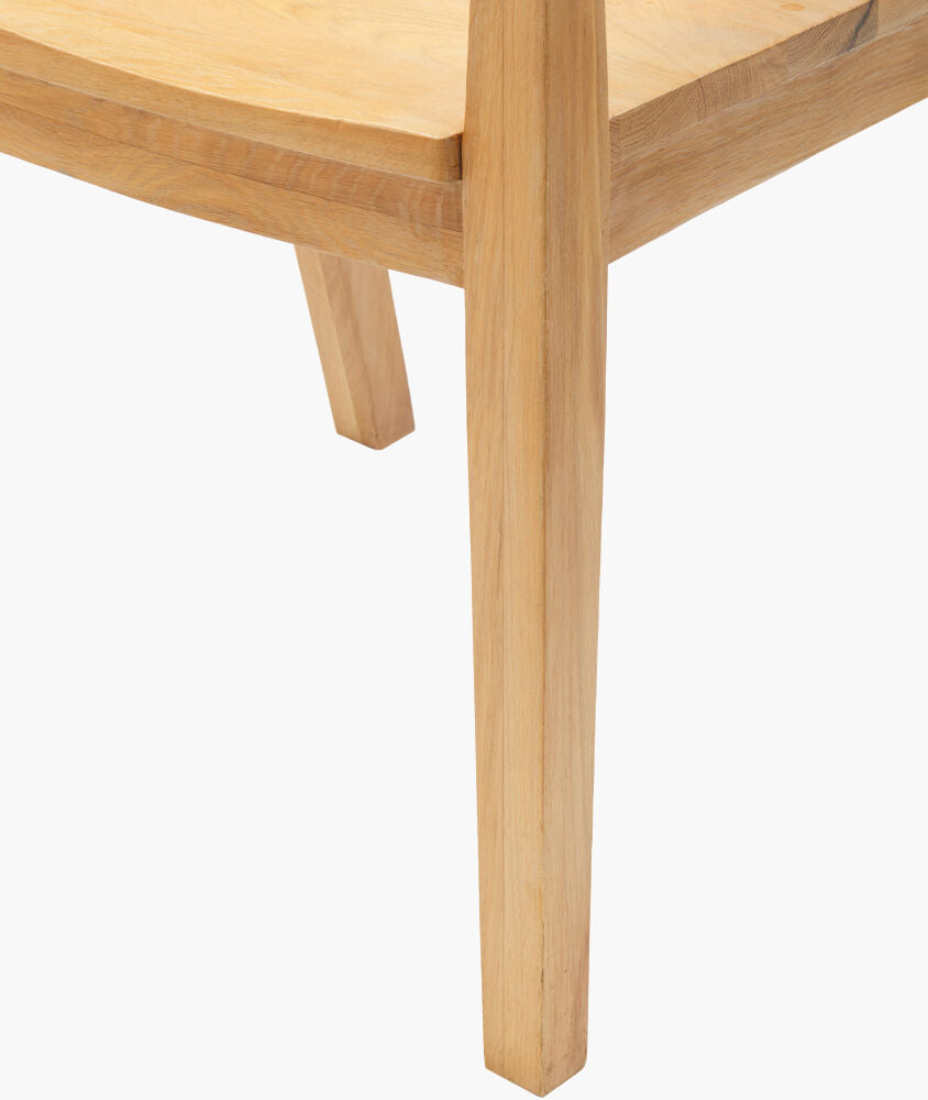 Close-up of the oak wood leg and seat edge of the modern chic dining arm chair, highlighting natural wood grain.