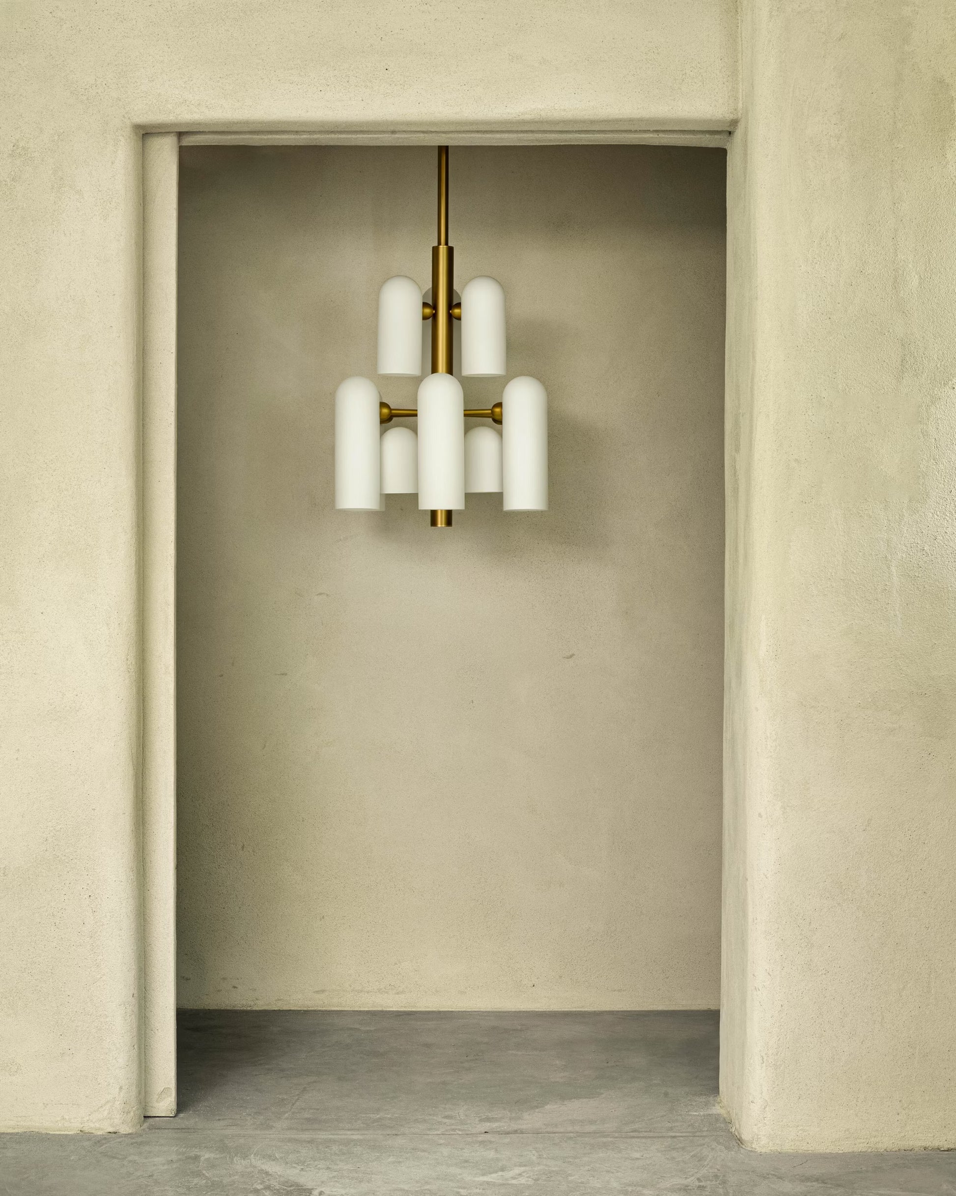 Odyssey 12 Chandelier in a minimalist setting, unlit, emphasizing its sculptural design and frosted glass shades.